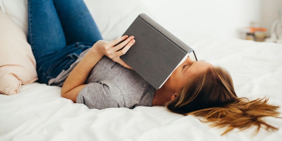 woman laying with a book on the bed
