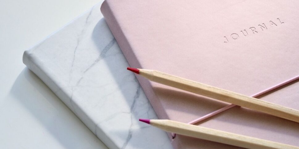 white and pink bullet journals and pens