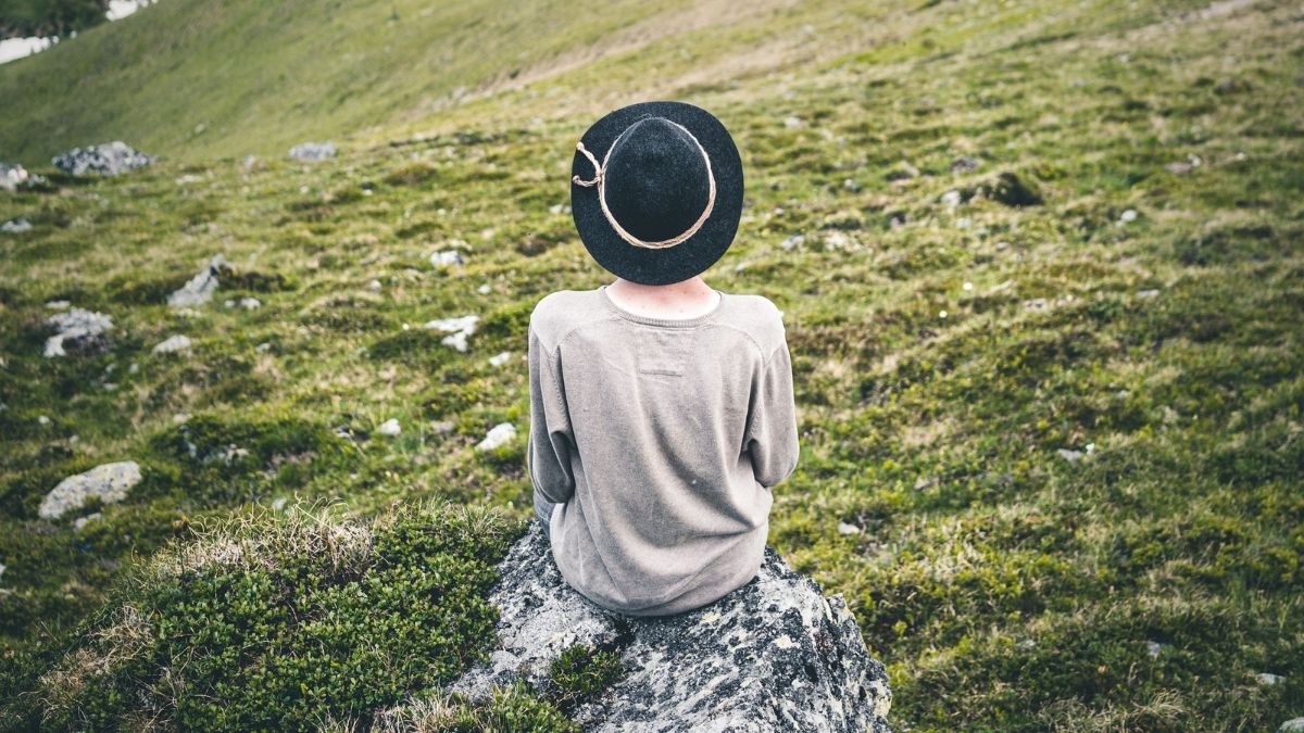 person sitting on a rock in a field