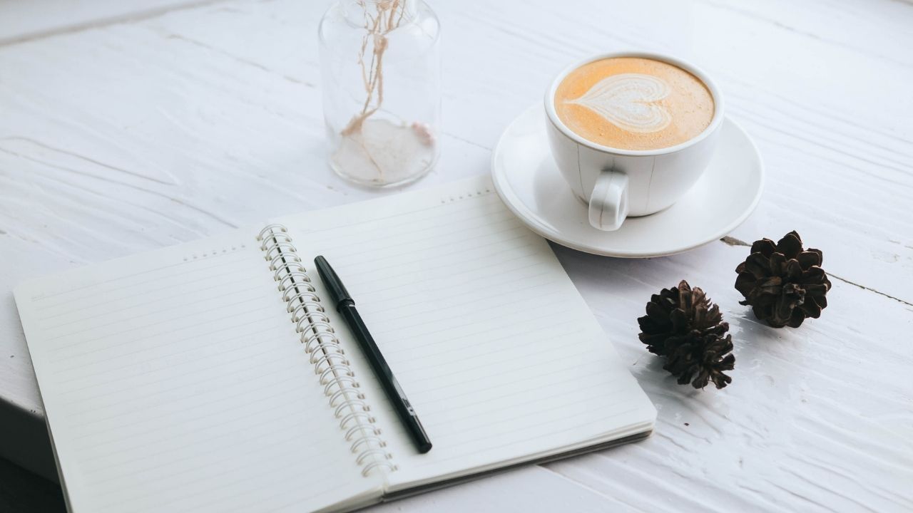 journal on table with coffee cup
