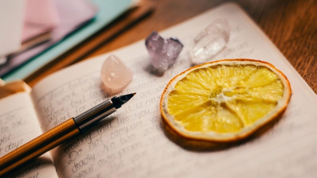 journal with pen and crystals and orange slice
