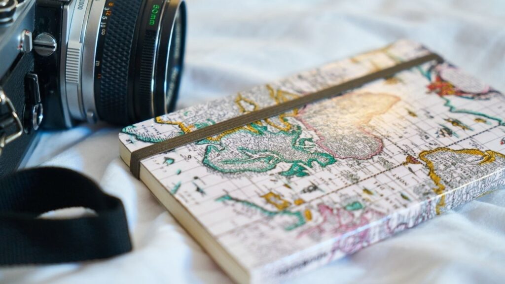 travel journal with map cover next to camera